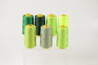 A collection of six spools of thread in various colors, including green, black, and lime green, arranged on a white background.