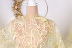 A mannequin wearing a yellow fabric with a floral pattern, displayed against a white background.
