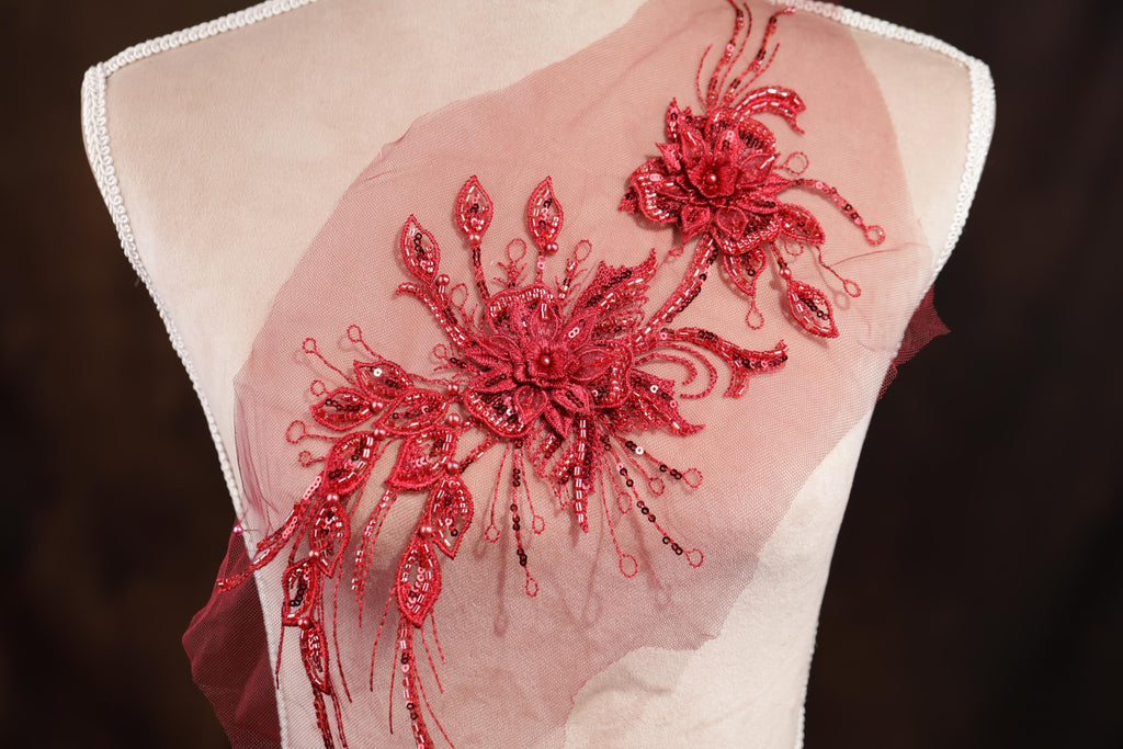 A mannequin wearing a dress with a red floral embellishment on the shoulder.
