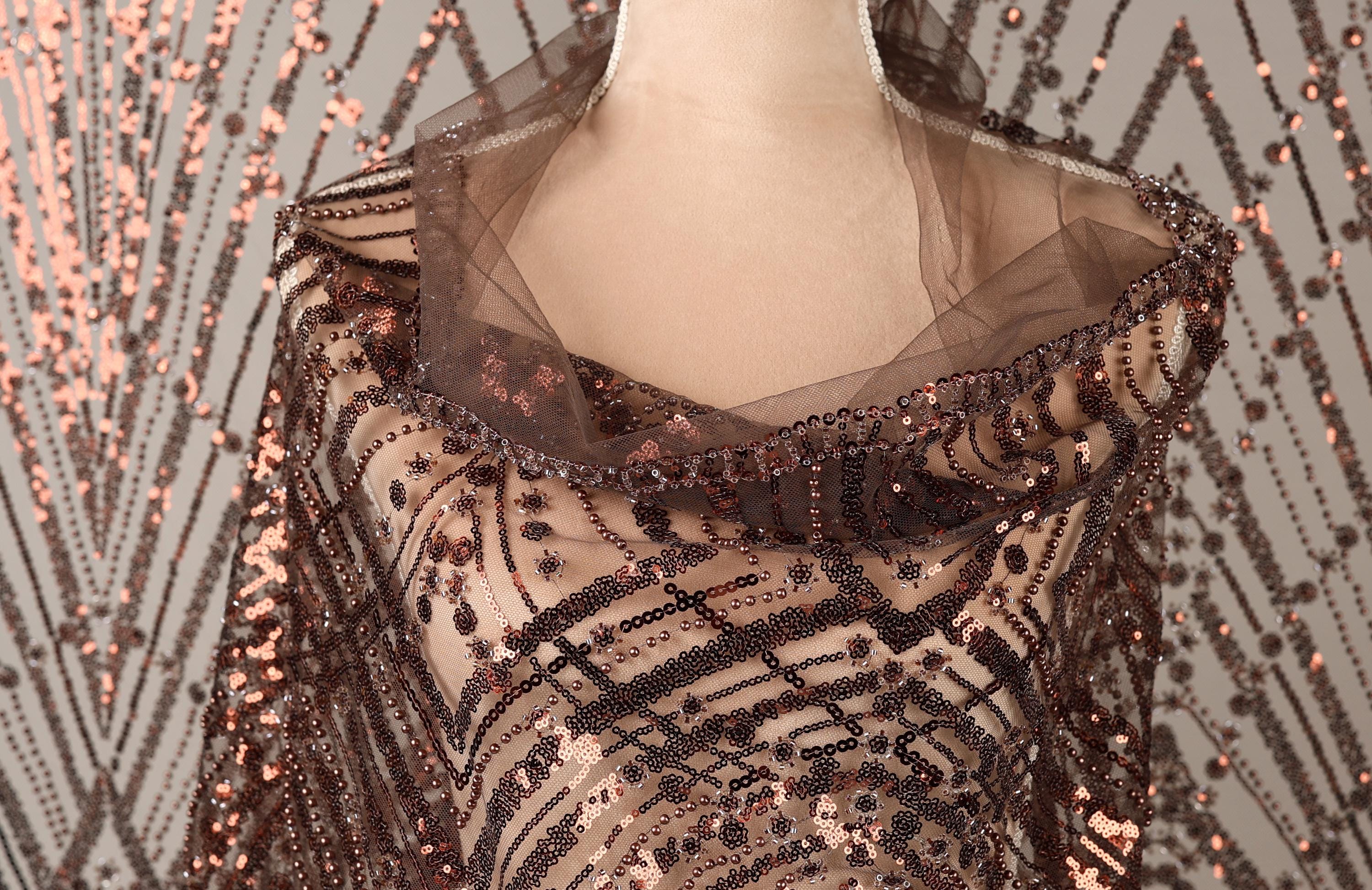 A mannequin wearing a brown sequin shawl with a sheer overlay.