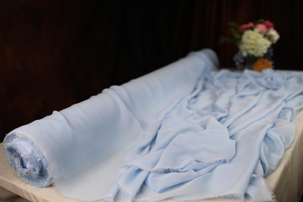 a bed with a blue blanket and a vase of flowers