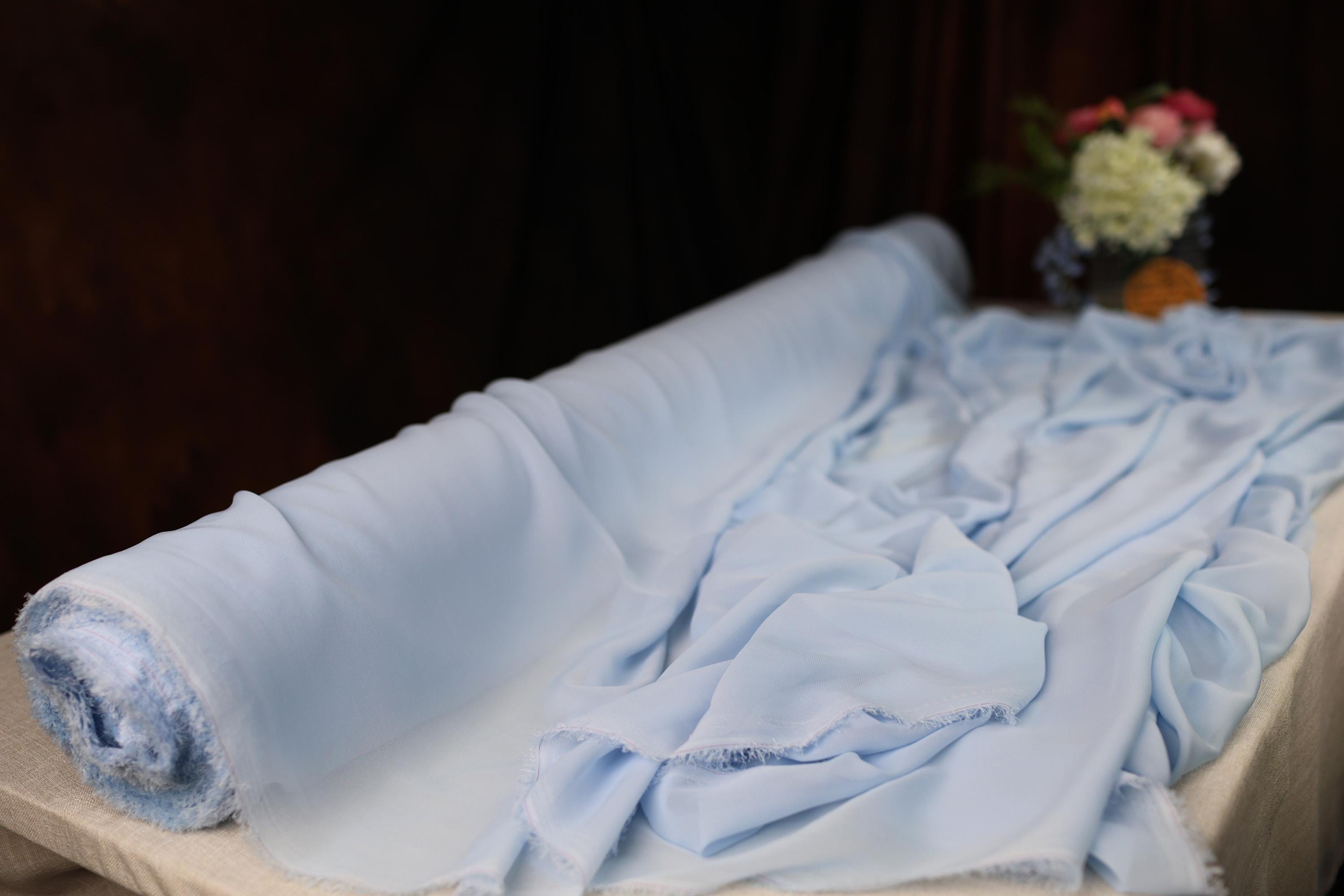 a bed with a blue blanket and a vase of flowers