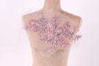 A mannequin with a sheer, lace-like fabric covering its upper body, adorned with a floral pattern in shades of pink and white.