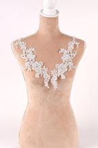 A mannequin wearing a white lace vest with delicate floral patterns.
