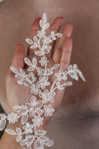 A hand holding a delicate white lace flower design.