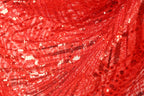 The image is a close-up of a red sequin fabric, showcasing its intricate and vibrant pattern.