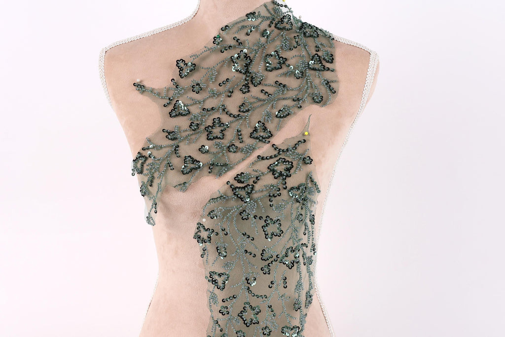 A mannequin wearing a dress with a green floral pattern and sequin accents.