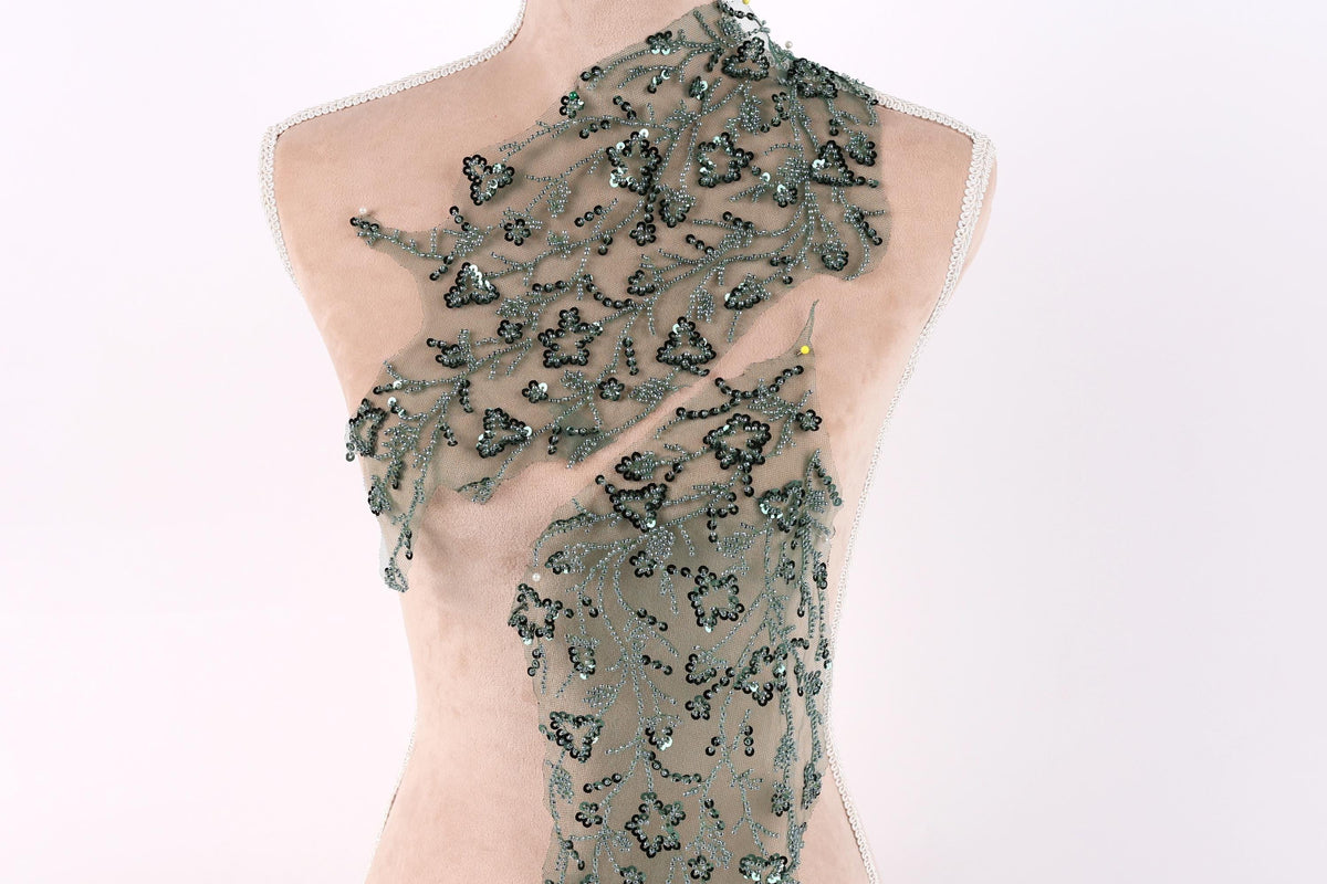 A mannequin wearing a dress with a green floral pattern and sequin accents.