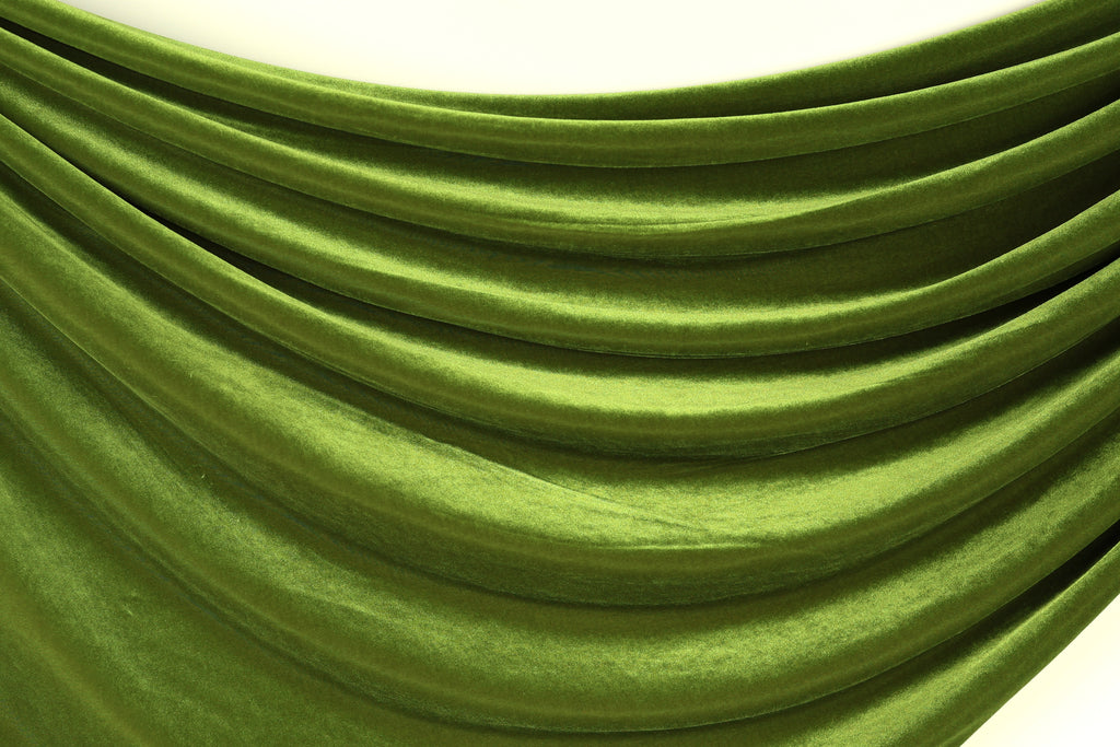 a close-up view of a shiny, green fabric with a smooth, flowing texture. The fabric appears to be made of a shiny, satin-like material, giving it a luxurious and elegant appearance.