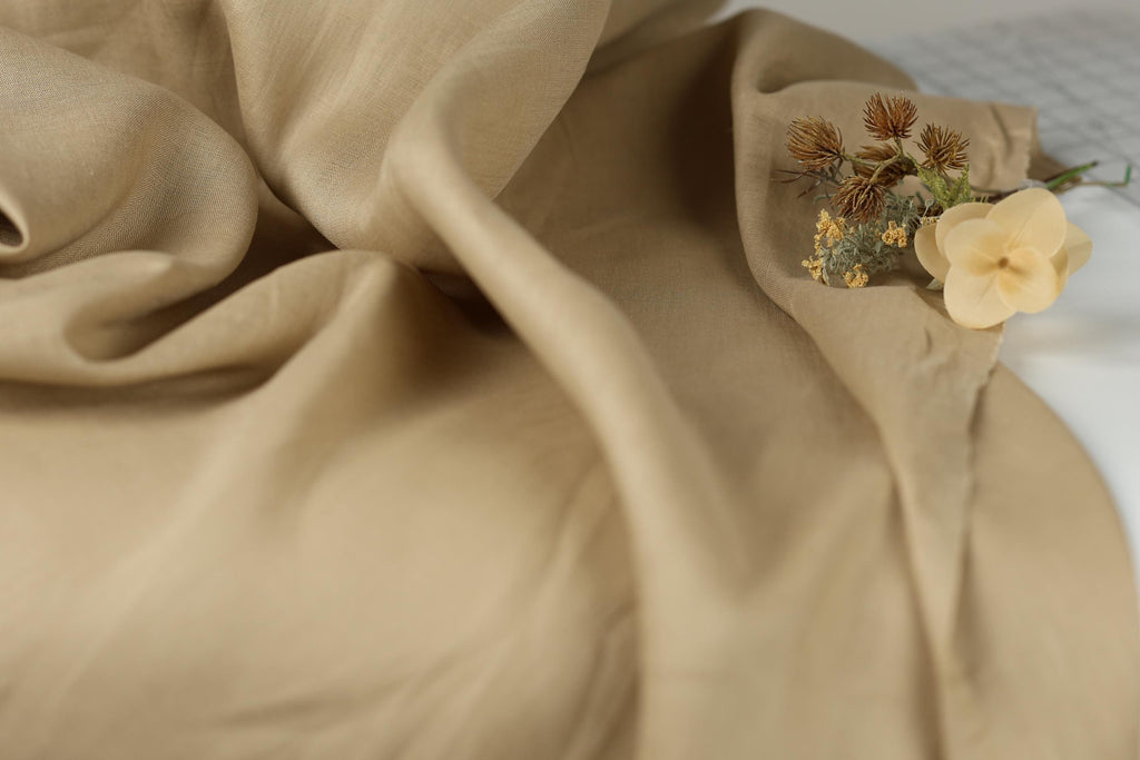 a close-up view of a beige fabric, with a small bouquet of flowers resting on it.