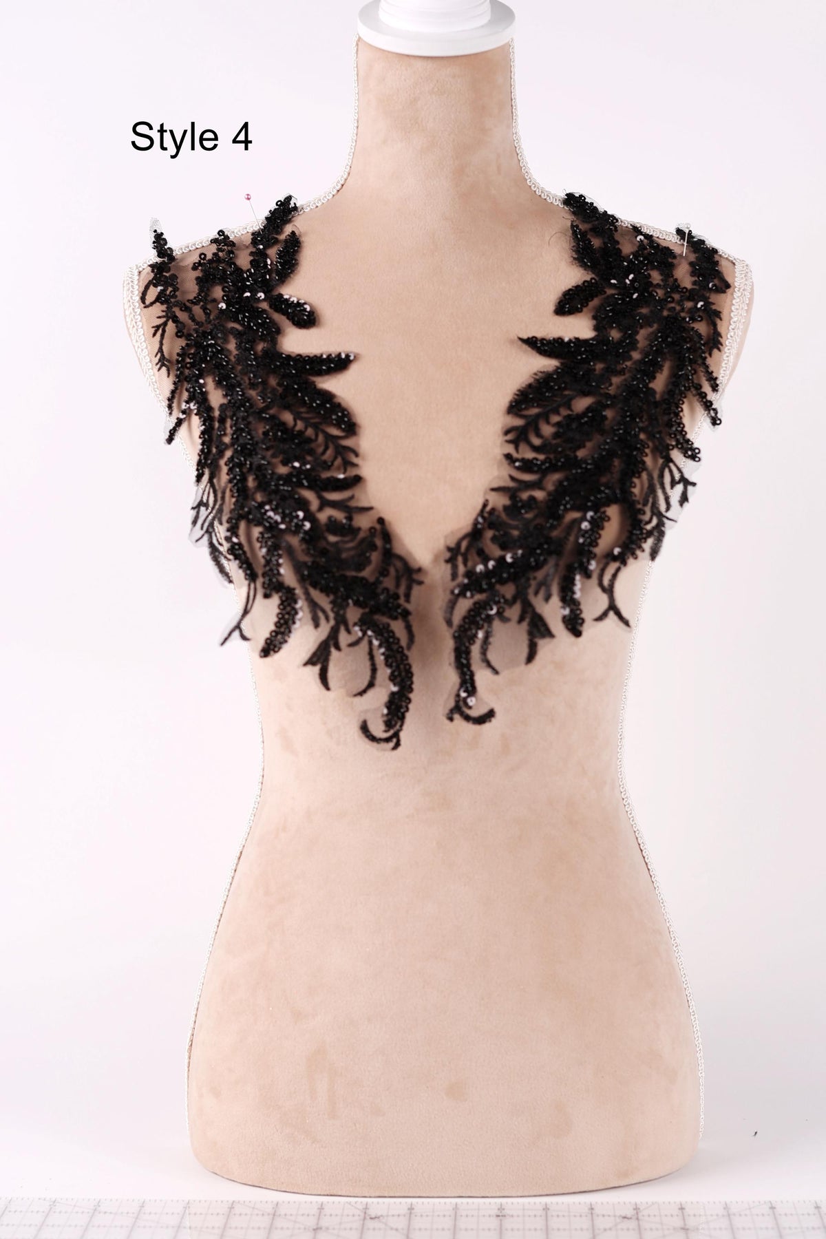 A mannequin wearing a black lace collar with intricate, feather-like embellishments.