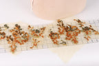 a close-up view of a piece of fabric with a floral pattern, featuring a ruler and a small beige object in the background.