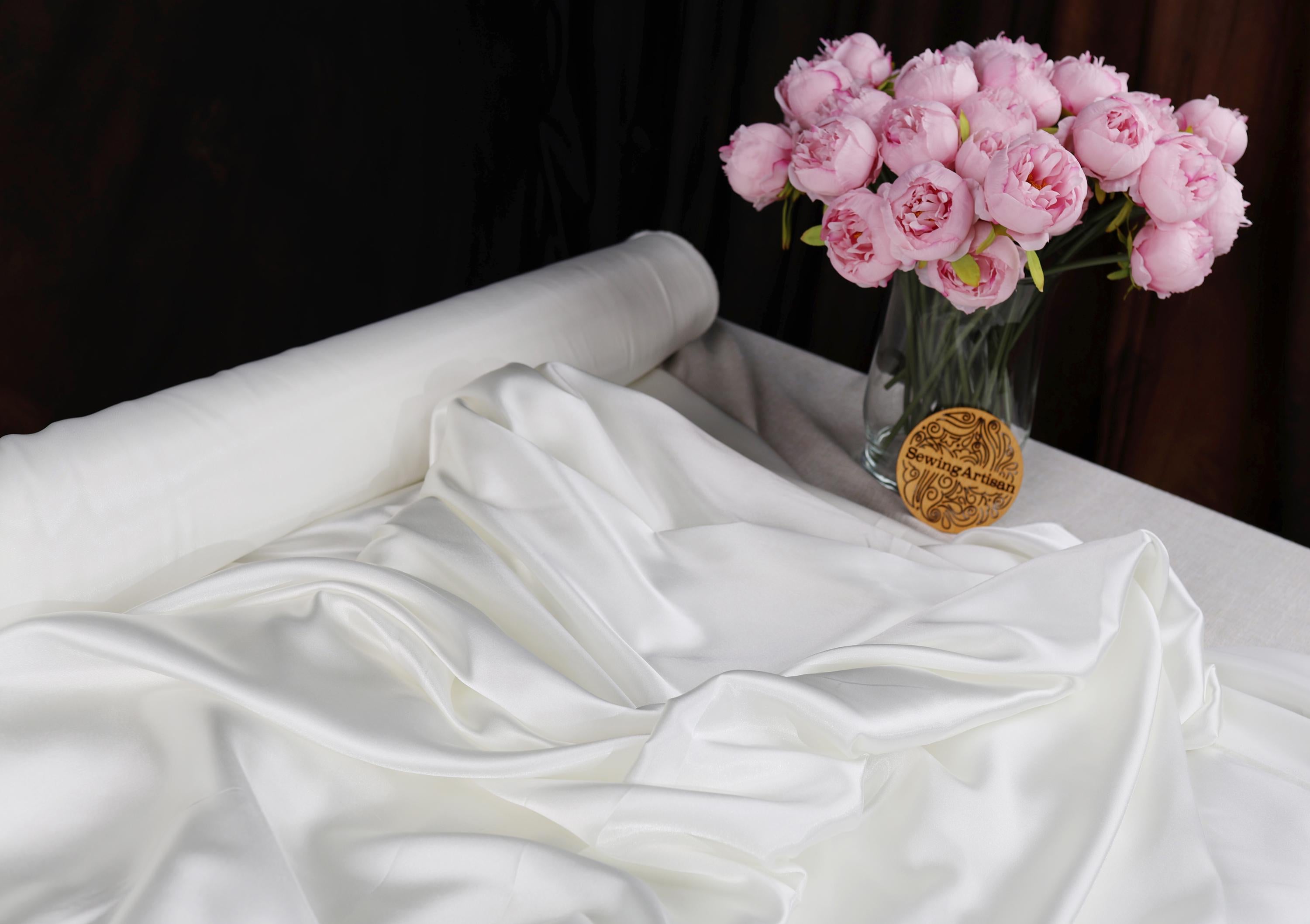 a vase filled with pink flowers sitting on top of a bed