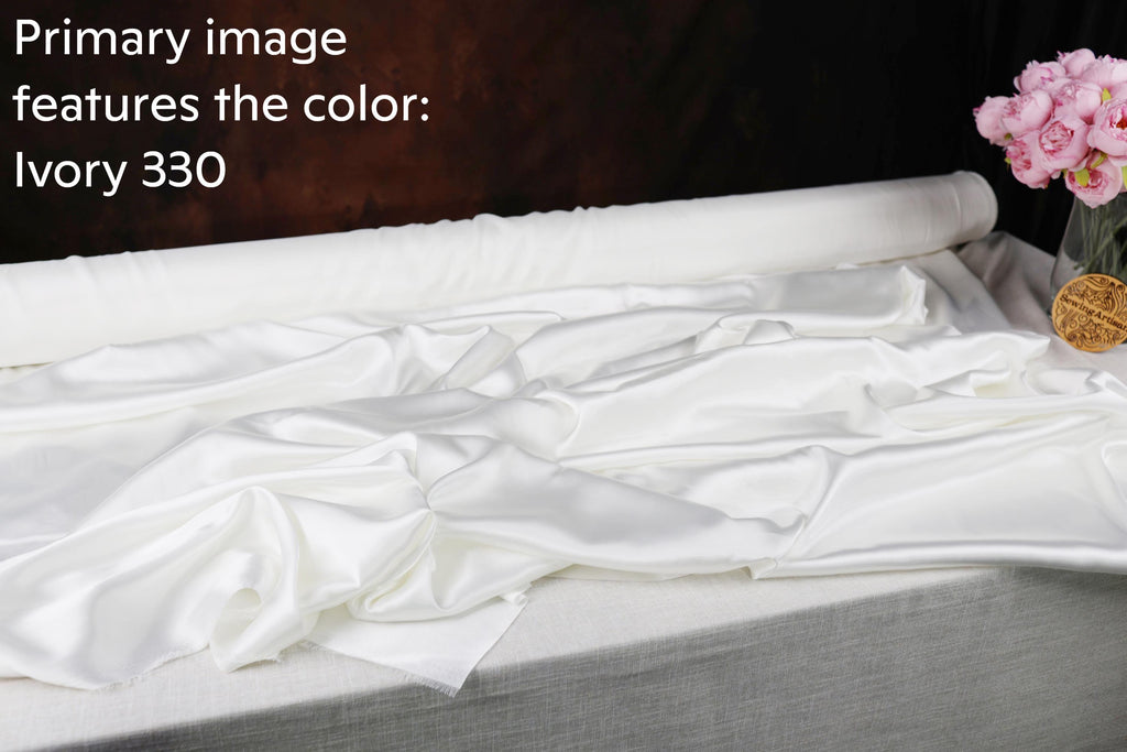 a roll of white satin fabric with a textured appearance, placed on a gray surface.