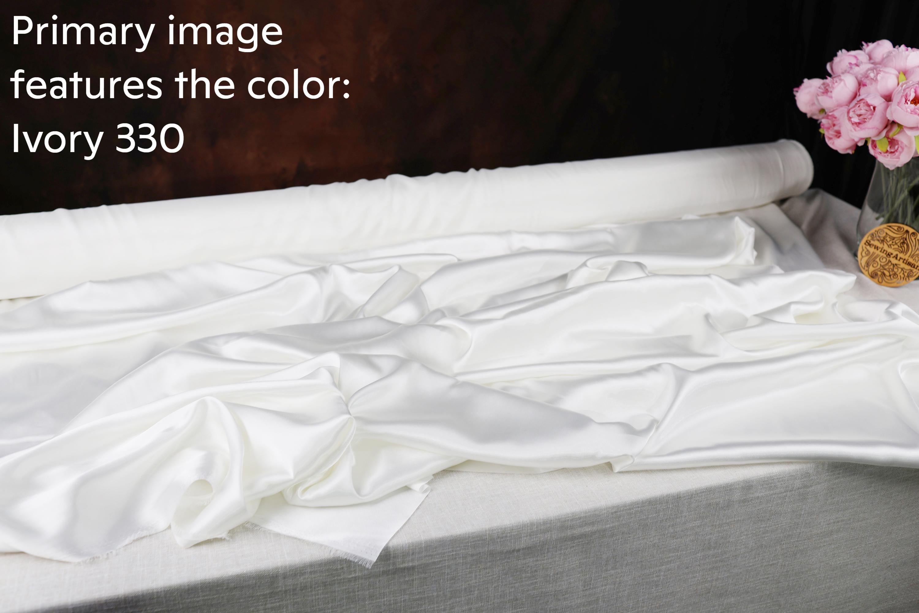 a roll of white satin fabric with a textured appearance, placed on a gray surface.