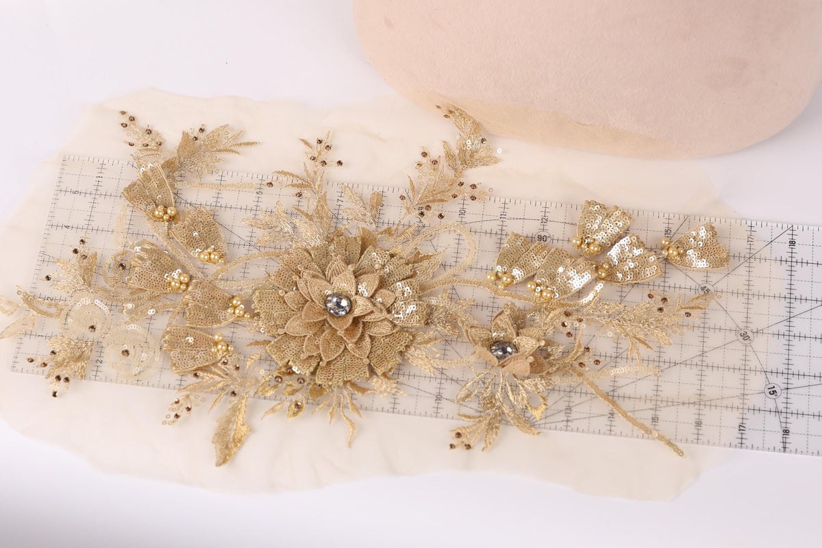 a close-up view of a delicate gold and white floral embroidery piece, with a ruler placed next to it.