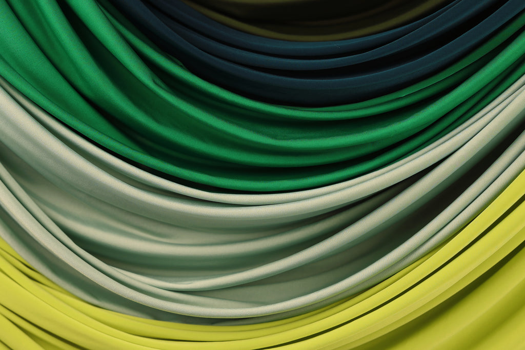 a close-up view of a collection of colorful fabric swatches, including shades of green, blue, and yellow.