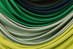 a close-up view of a collection of colorful fabric swatches, including shades of green, blue, and yellow.