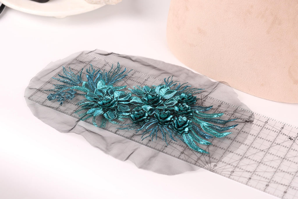 a close-up view of a piece of fabric with a floral design, including blue and green flowers, placed on a ruler.