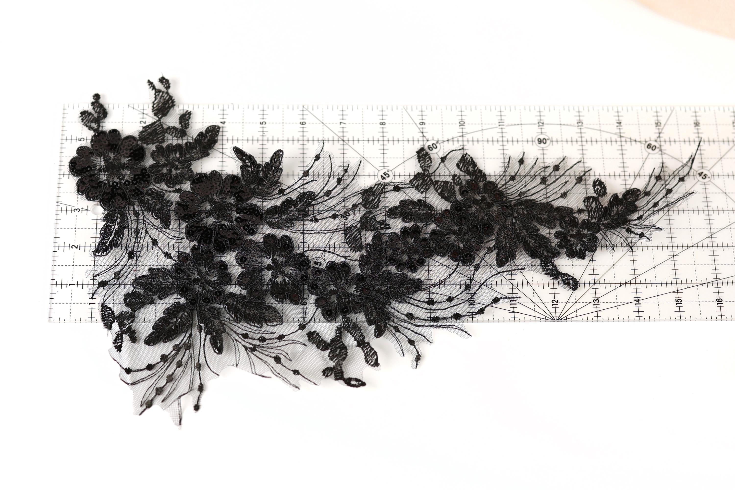 a close-up view of a black lace flower pattern on a ruler, with the ruler providing a scale reference.