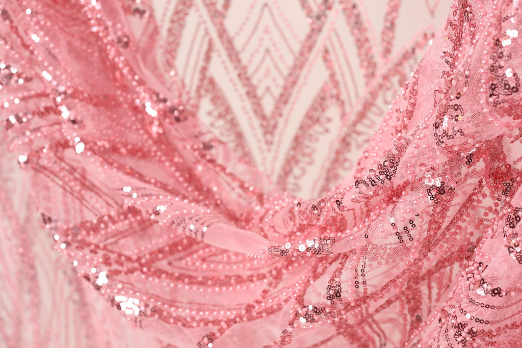 A close-up view of a pink sequin fabric, with intricate patterns and designs visible.
