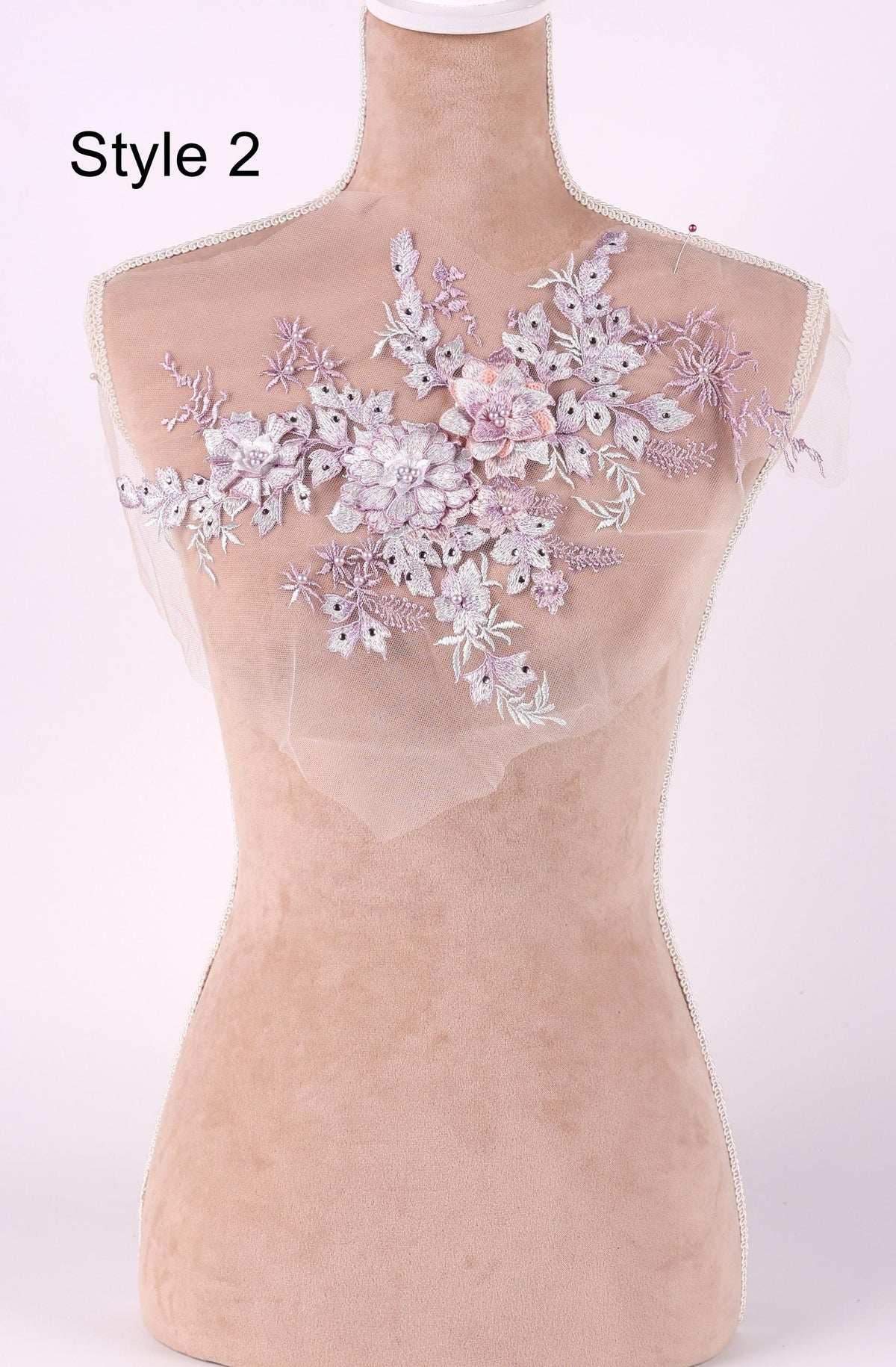 A mannequin with a floral embroidered piece of fabric on its shoulder.