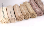 A collection of rolled-up fabric swatches in various shades of beige, including champagne, nutmeg, coffee, kaki, rosewood, and mocha.