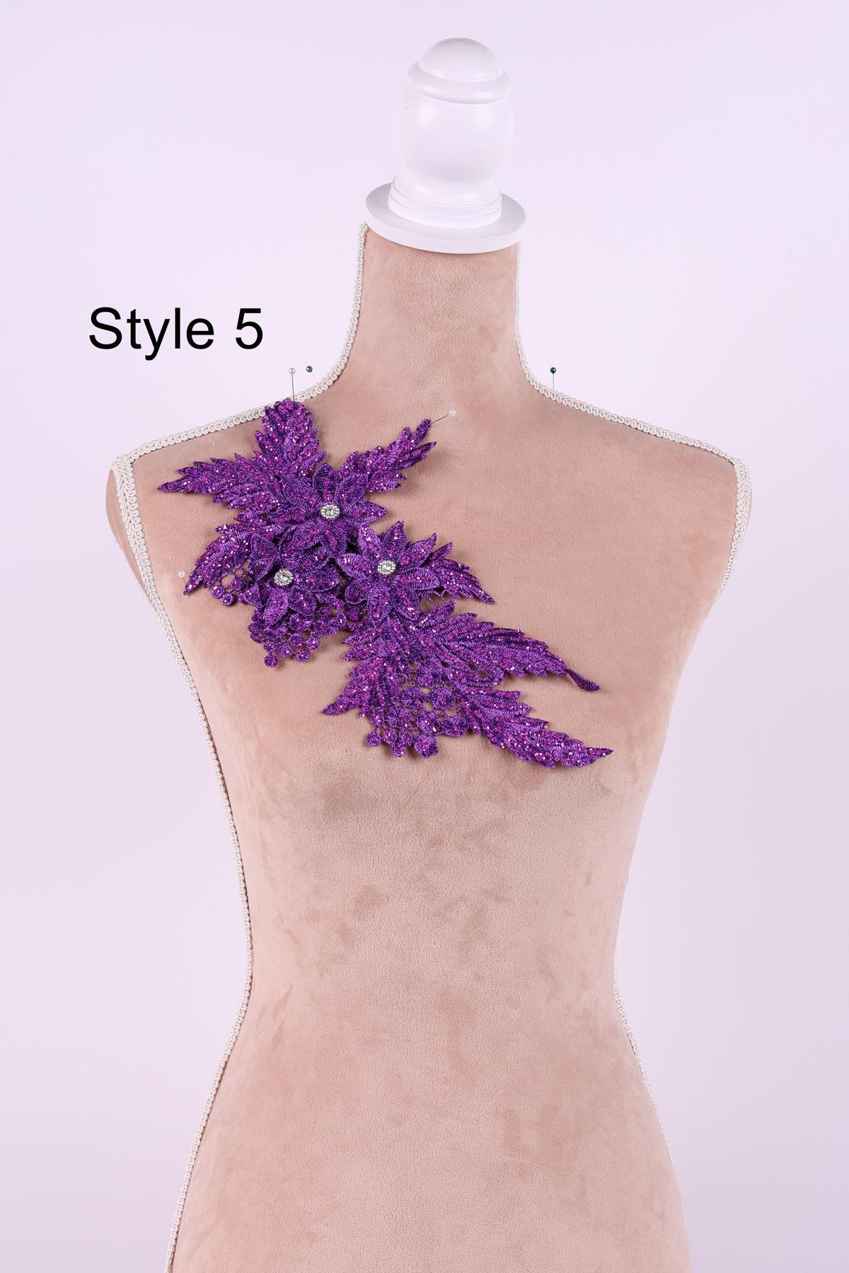 A mannequin with a purple, glittery leaf-shaped embellishment on its shoulder.