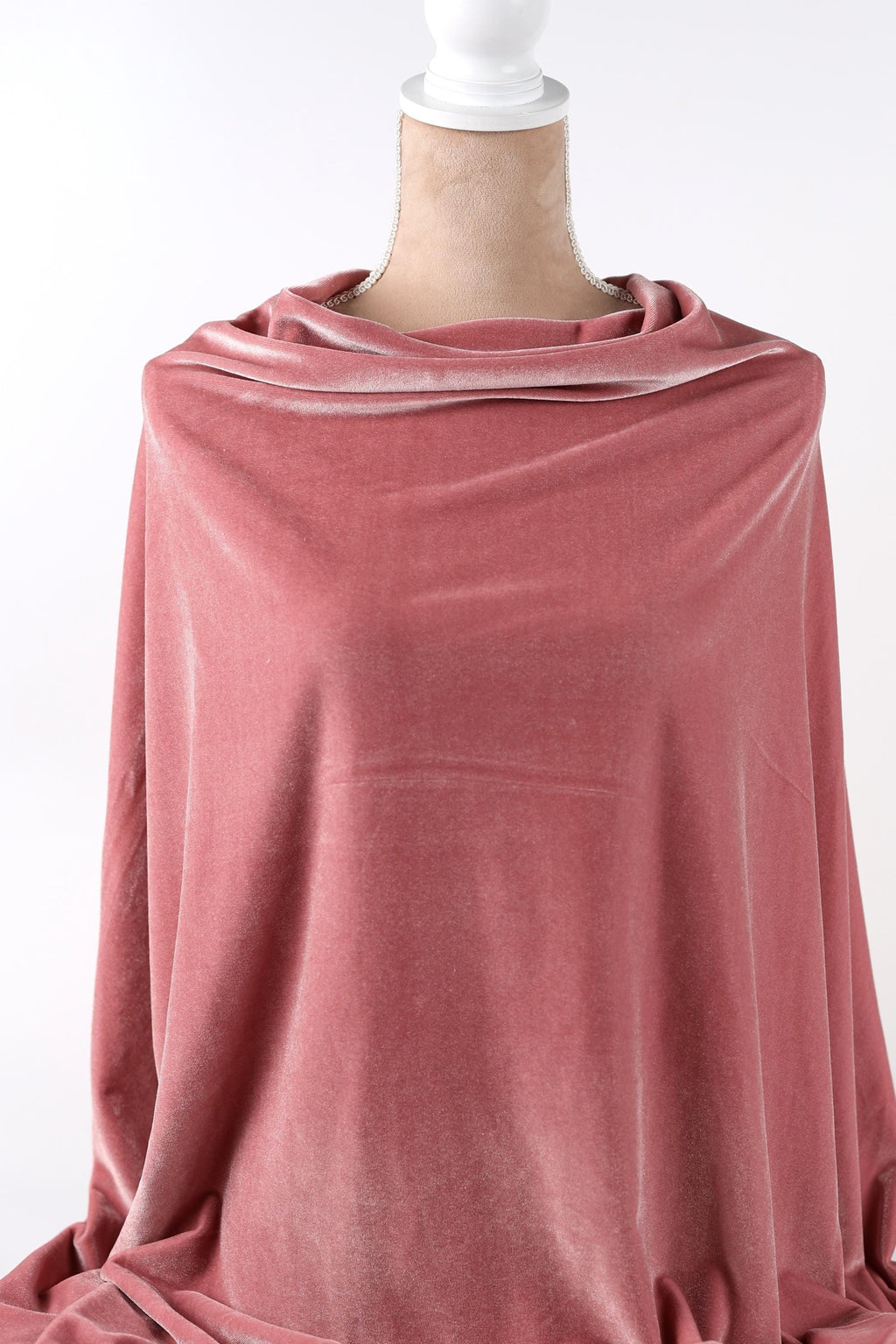A mannequin wearing a pink velvet fabric draped over its body.