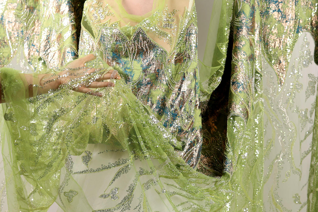 A close-up view of a green and silver sequined dress, with the fabric appearing to be made of sheer material.