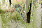 A close-up view of a green and silver sequined dress, with the fabric appearing to be made of sheer material.