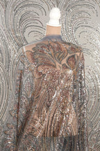 a mannequin wearing a shimmering, sequined dress with a floral pattern. The dress has a sheer back and long sleeves, giving it a delicate and elegant appearance.