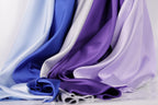 a variety of colorful satin fabrics, including blue, purple, and white, arranged in a visually appealing manner.