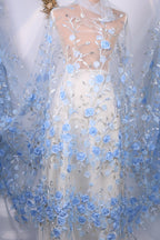 A white dress with a sheer blue floral overlay, featuring delicate blue flowers and leaves.