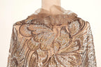 a close-up view of a beige and gold sequined dress with a ruffled collar and a floral pattern.