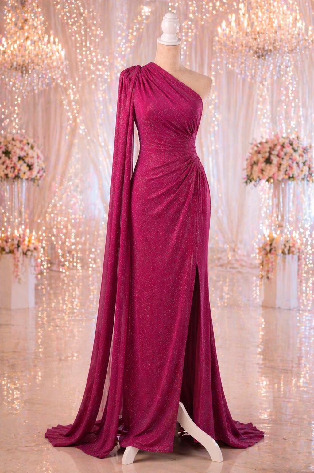 A long, one-shoulder pink gown with a high slit on the side, displayed on a mannequin.