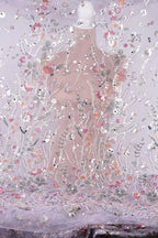 a close-up view of a delicate, intricately embroidered fabric with a floral pattern. The fabric appears to be made of sheer material, allowing the colorful flowers and leaves to be clearly visible. The image does not contain any text or other discernible objects, and the focus is solely on the detailed embroidery work.
