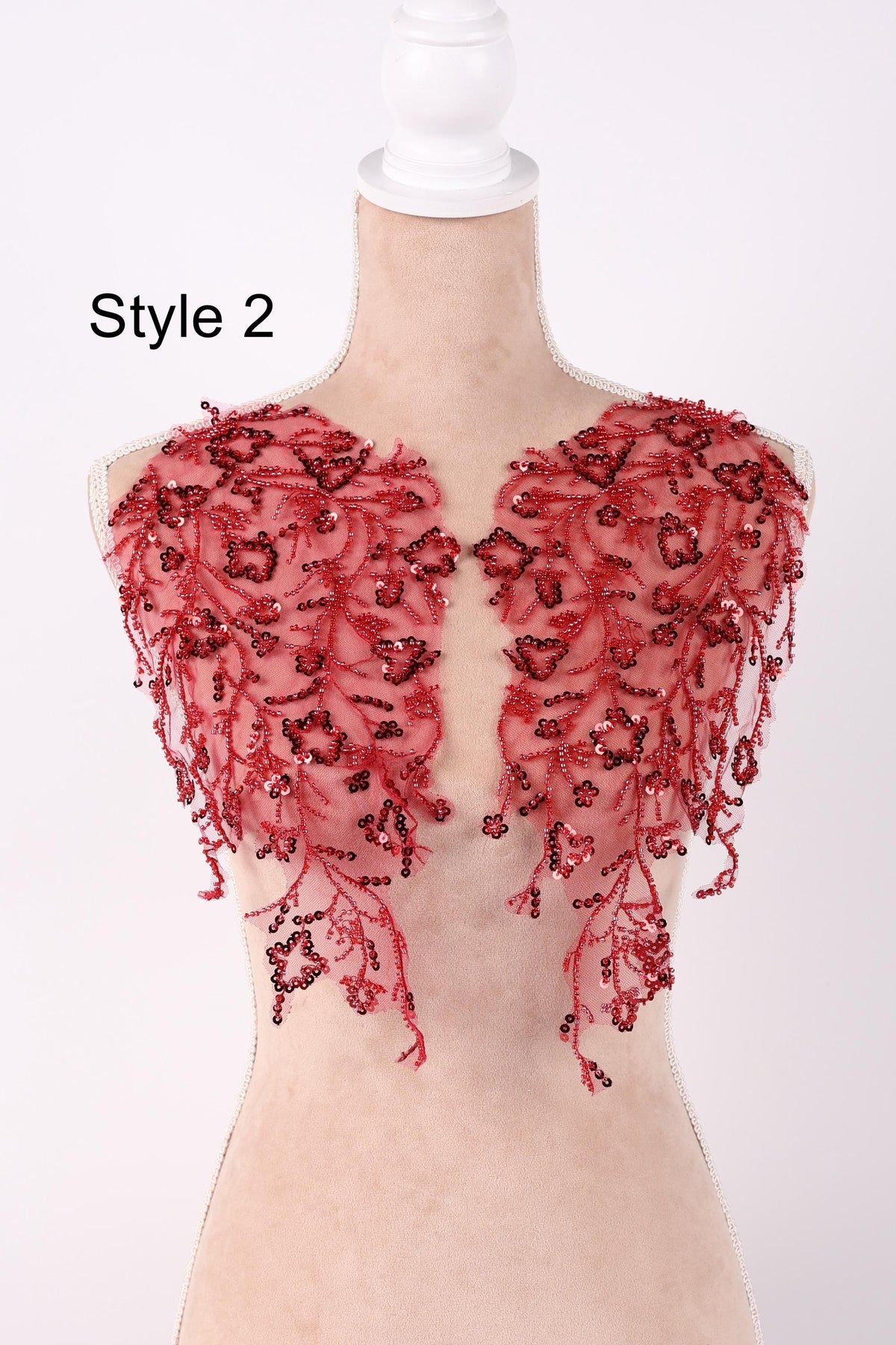 A mannequin wearing a red, embellished dress with a floral pattern.