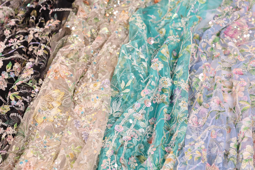 a variety of colorful, intricately embroidered fabric pieces, including a teal fabric with a floral pattern and a black fabric with a floral pattern. The fabric pieces are arranged in a row, showcasing the different designs and colors.