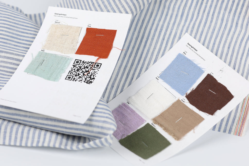 two pieces of paper with fabric swatches and QR codes, placed on a striped fabric background.