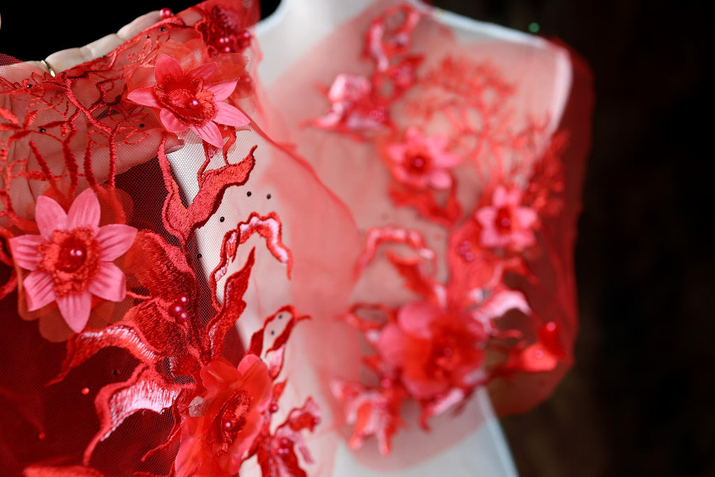 A close-up view of a red, intricately embroidered dress with delicate pink flowers.