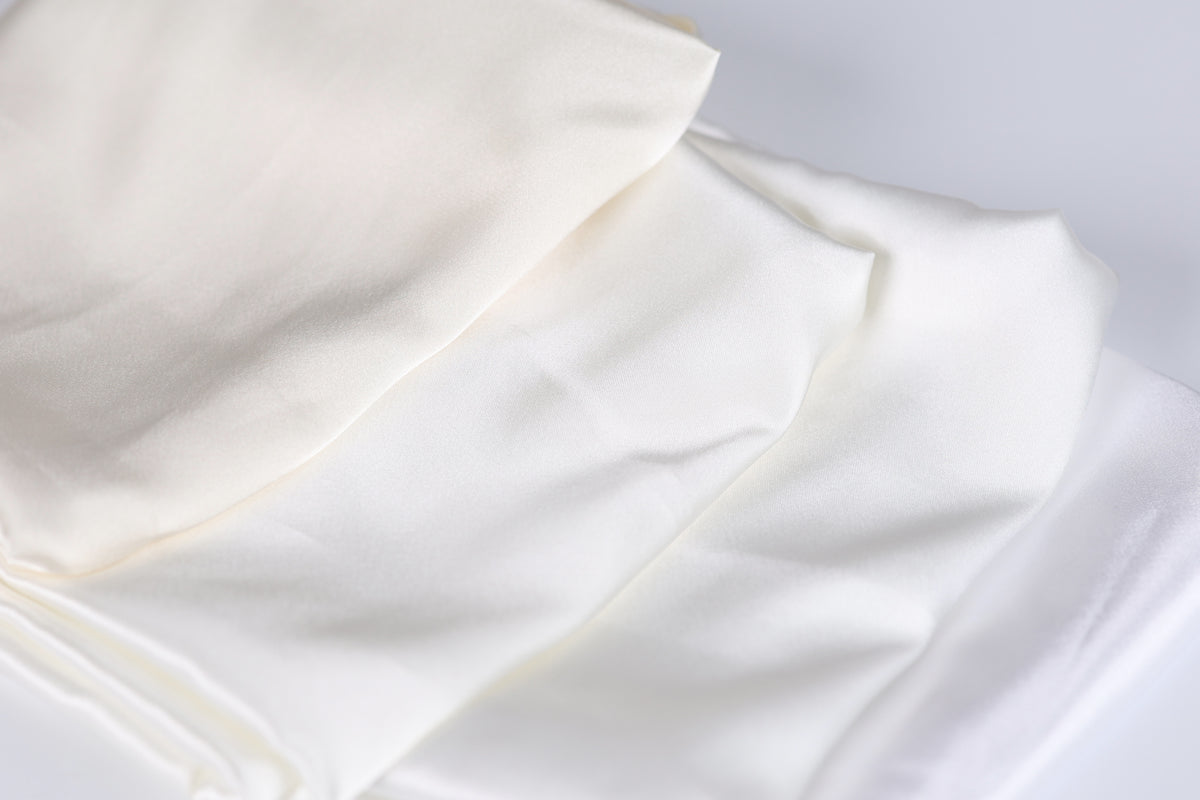 a close-up view of a white fabric, possibly a piece of clothing or a textile, with a slightly wrinkled texture.