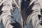 The image is a close-up of a fabric with a striking pattern of sequins and beads in shades of blue, black, and gold. The pattern is intricate and detailed, with the sequins and beads arranged in a way that creates a visually captivating design.