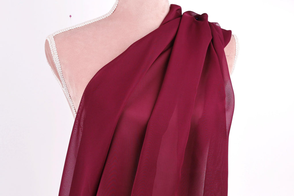 A mannequin wearing a red chiffon scarf draped over its shoulder.