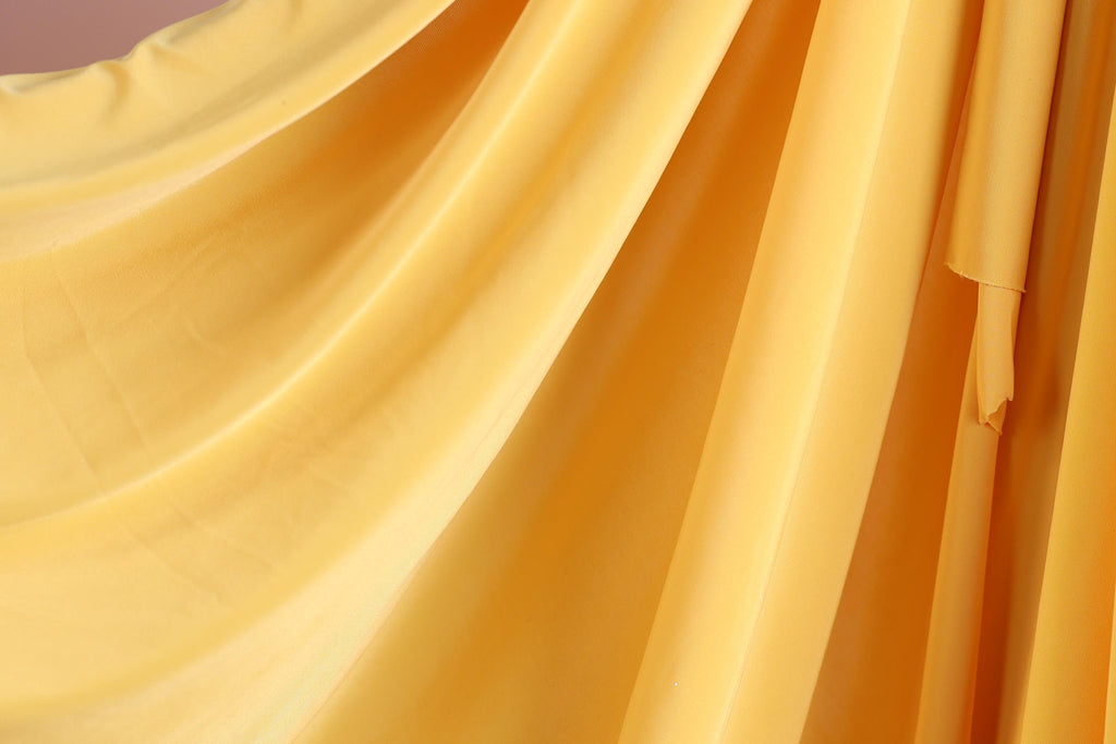 a close-up view of a yellow fabric, possibly a curtain or drape, with a soft, flowing texture.