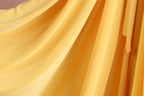 a close-up view of a yellow fabric, possibly a curtain or drape, with a soft, flowing texture.