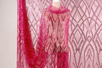 a pink sequin fabric with a pink and white patterned background.