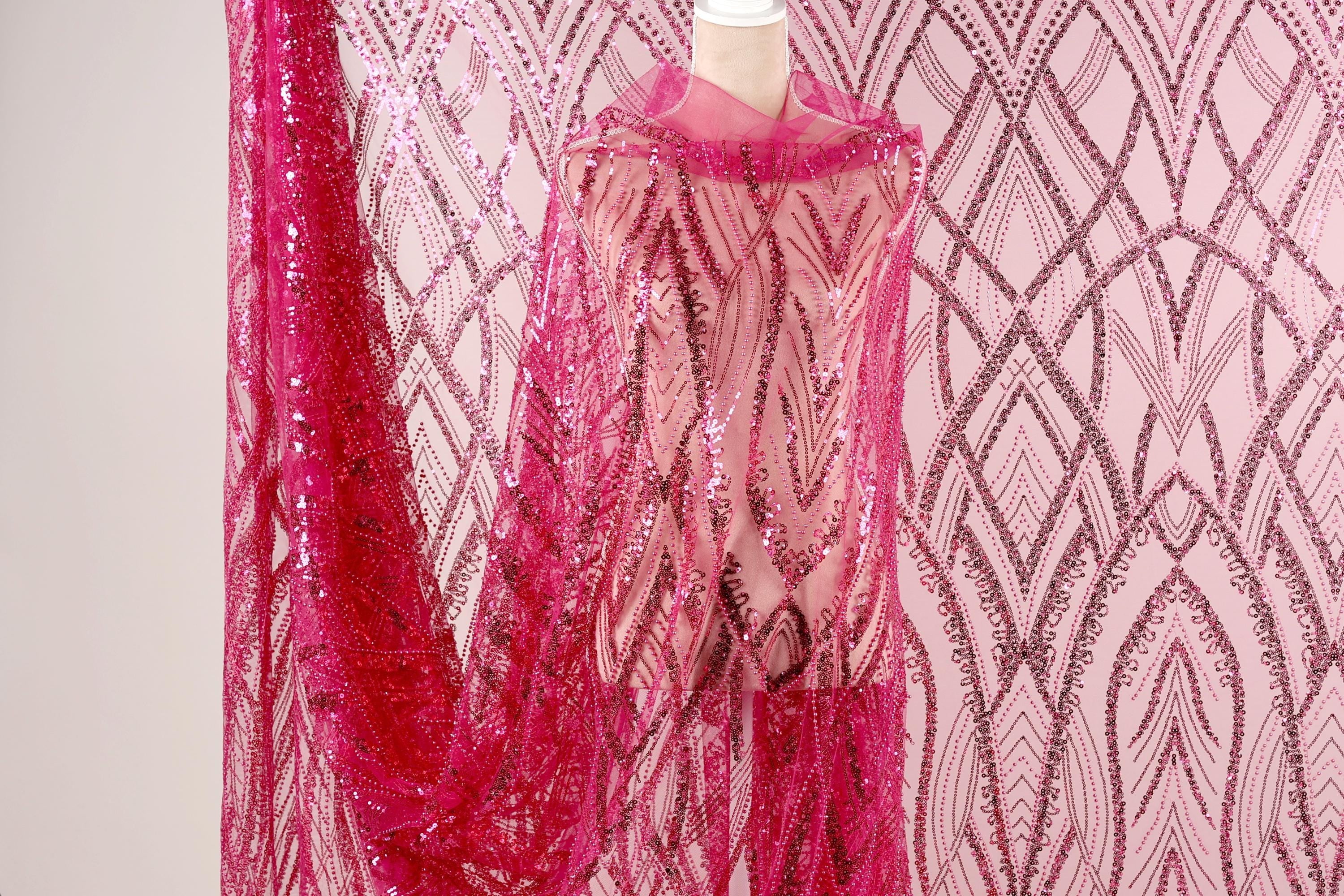 a pink sequin fabric with a pink and white patterned background.