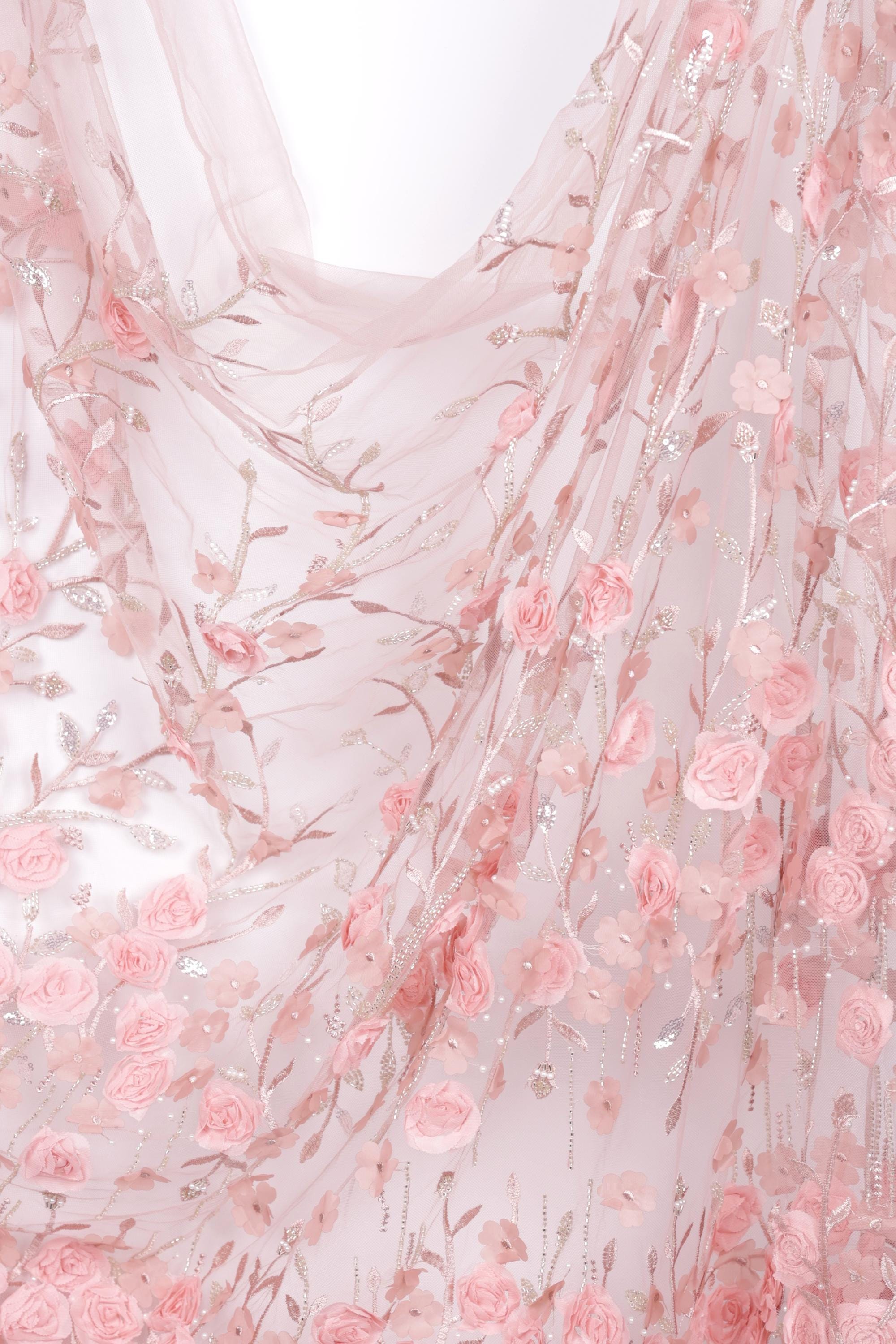 a delicate and intricate piece of fabric adorned with a floral pattern of pink roses and leaves. The fabric appears to be made of sheer material, giving it a soft and delicate appearance. The floral design is spread across the fabric, creating a visually appealing and harmonious pattern.