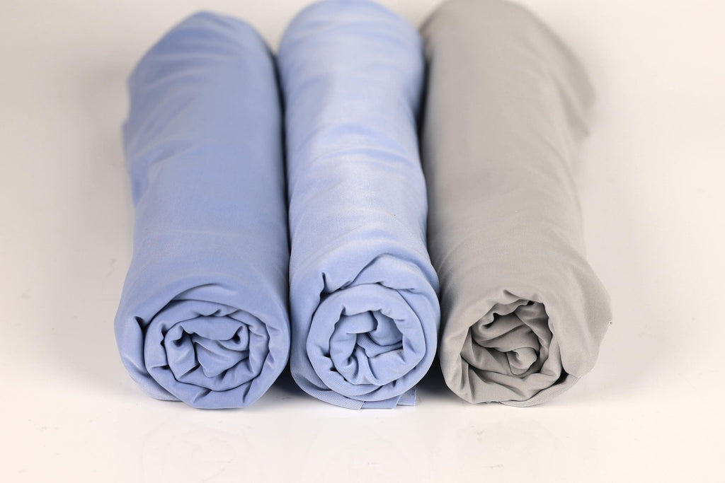 Three rolled-up blue and gray towels are arranged in a row on a white background.
